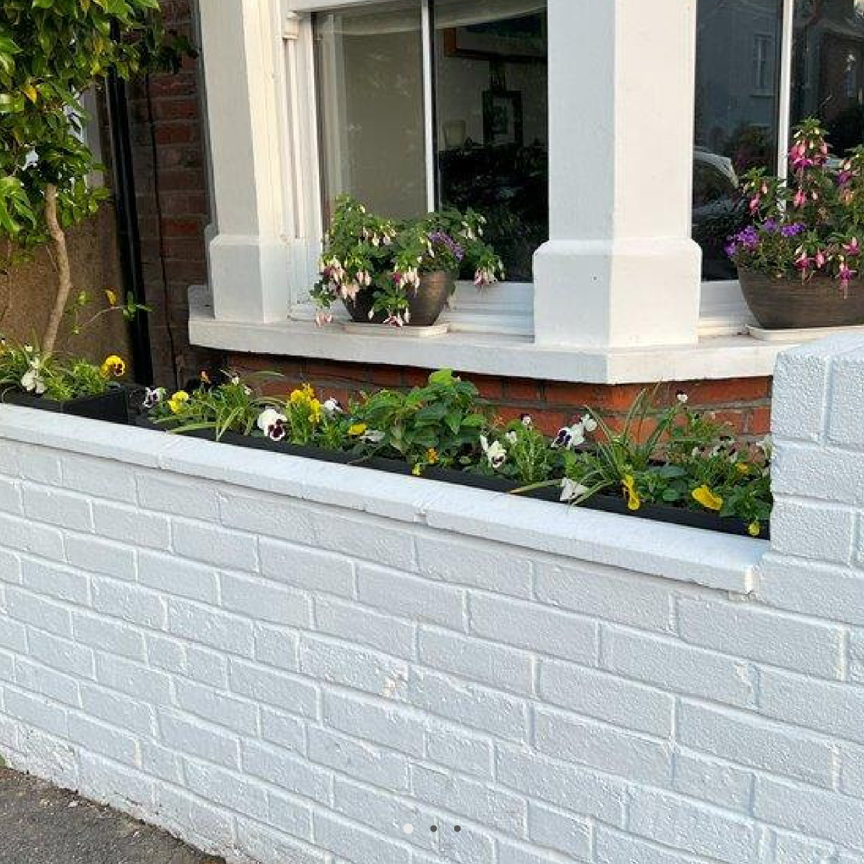 Brick planter with flowers in front of a building